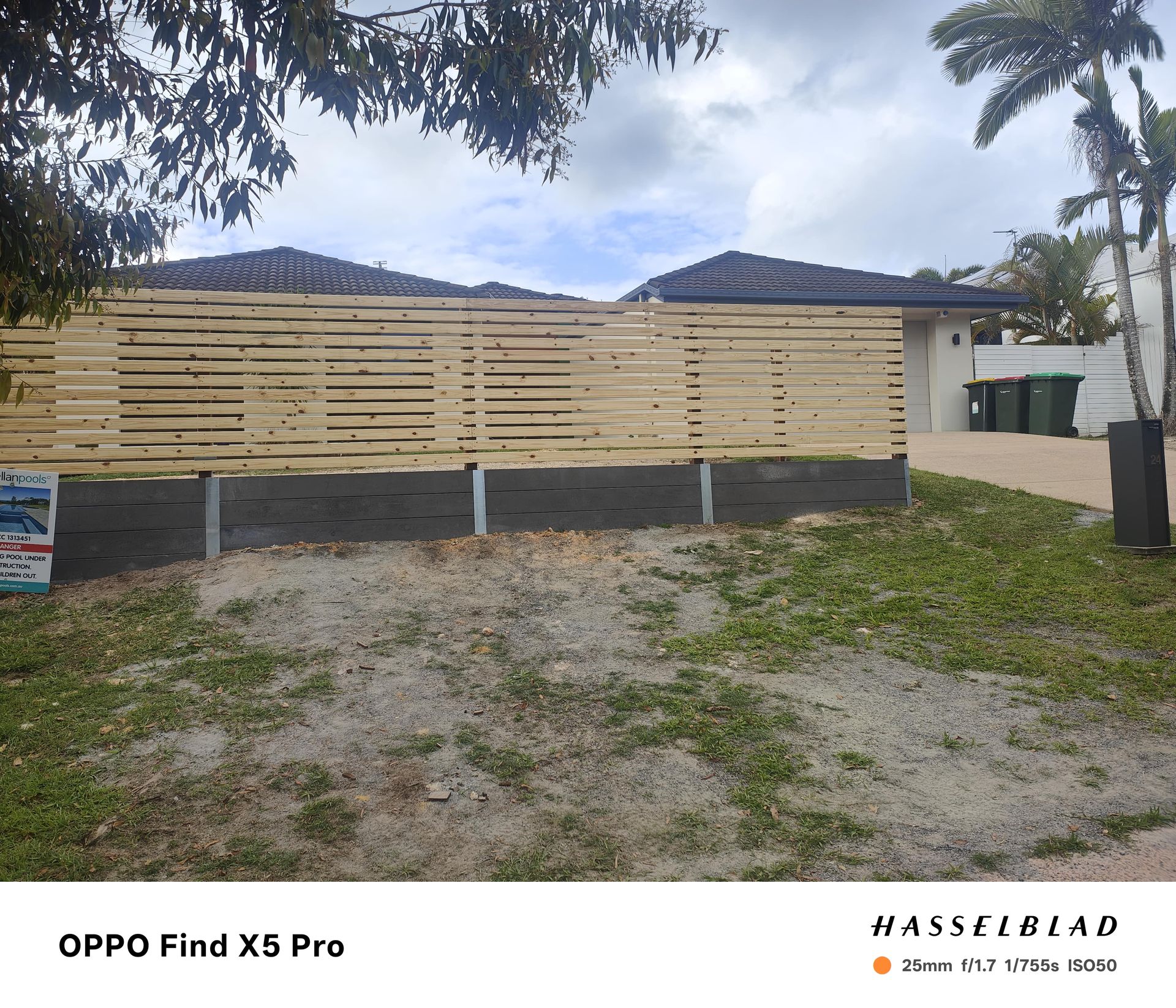 Wooden fence in front of a house, set against a cloudy sky — Quality Fences 4 U in Gympie, QLD