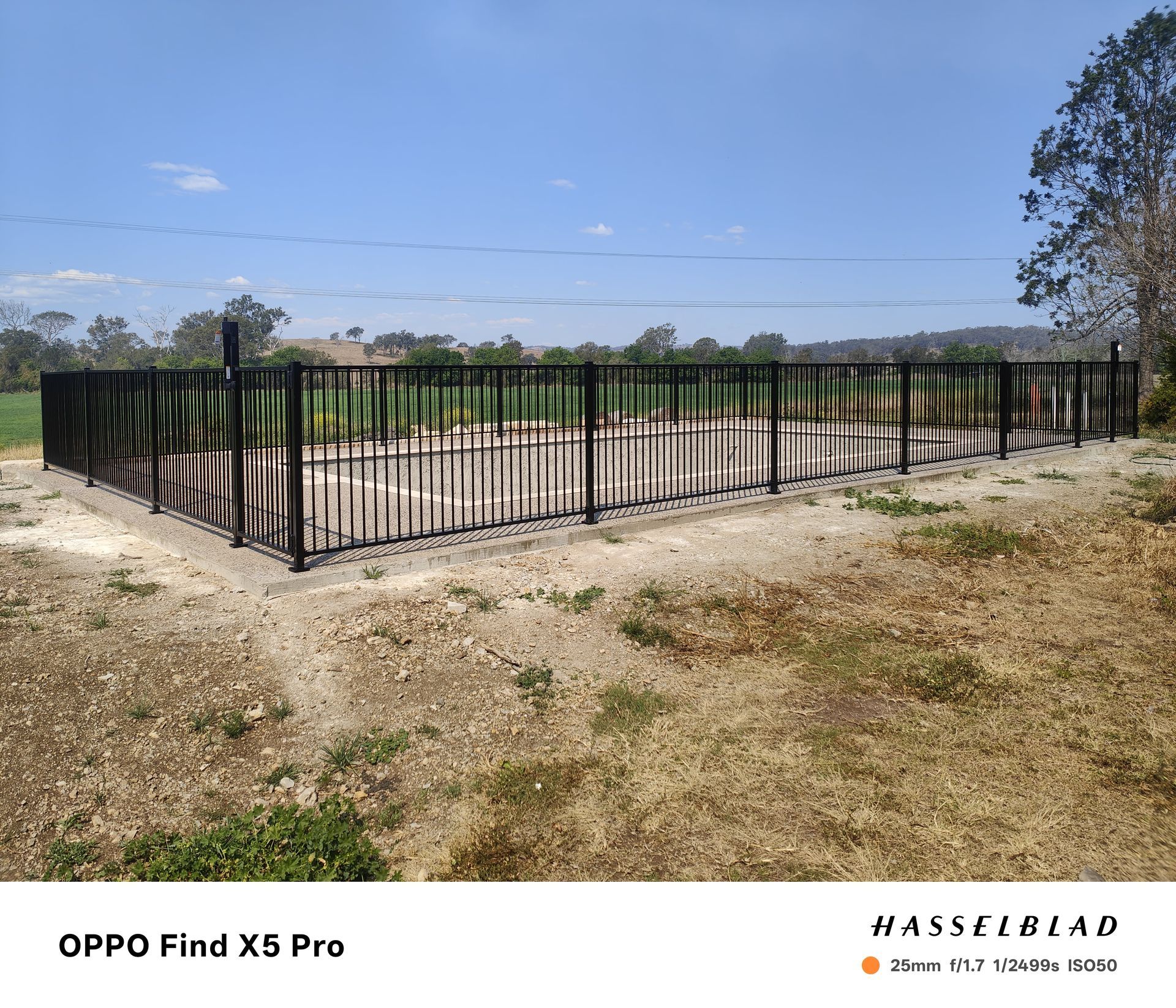 Black metal fence enclosure on dirt, under a blue sky — Quality Fences 4 U in Gympie, QLD