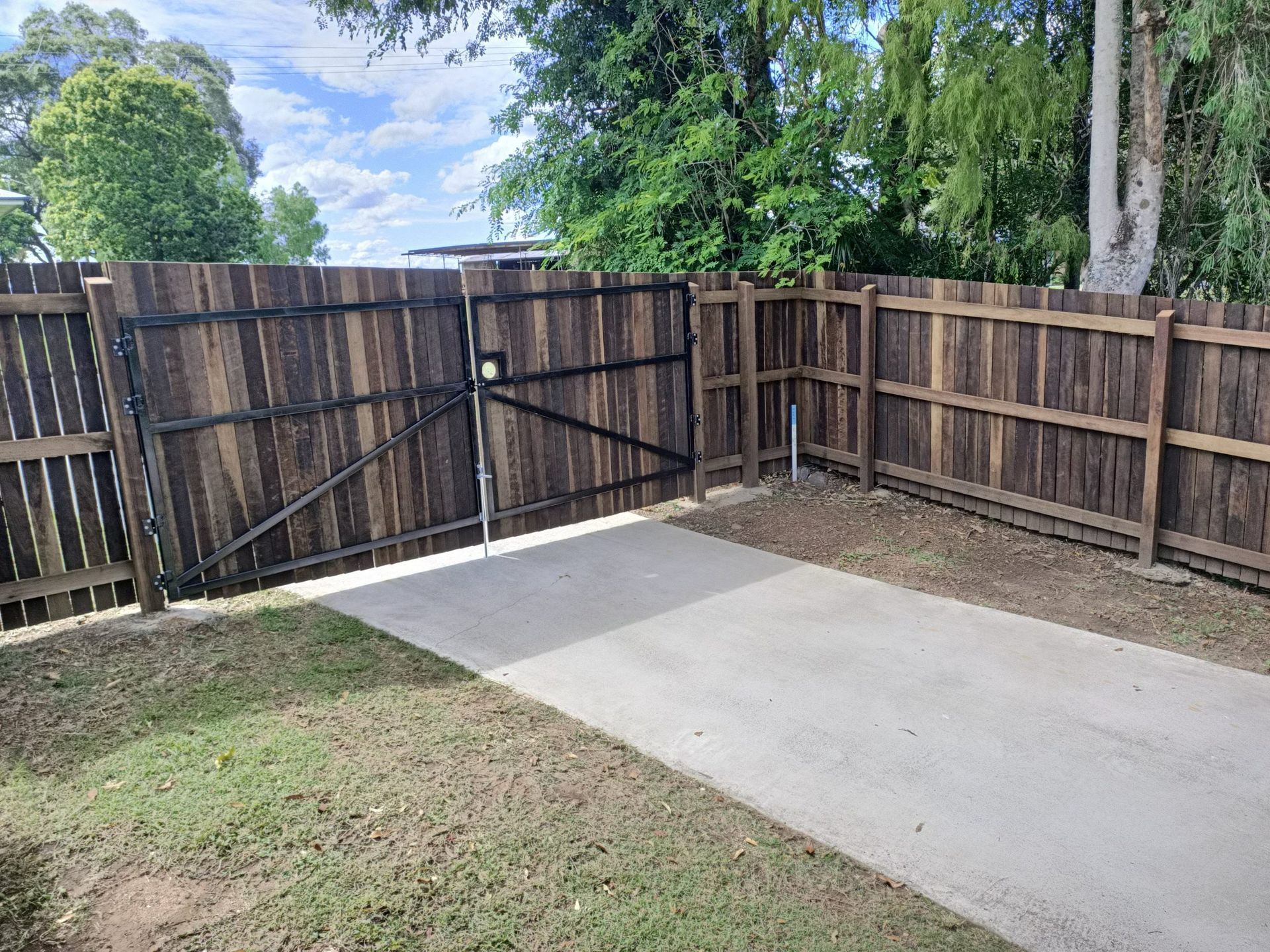 Driveway With Wooden Fence and Black Gate — Quality Fences 4 U in Gympie, QLD