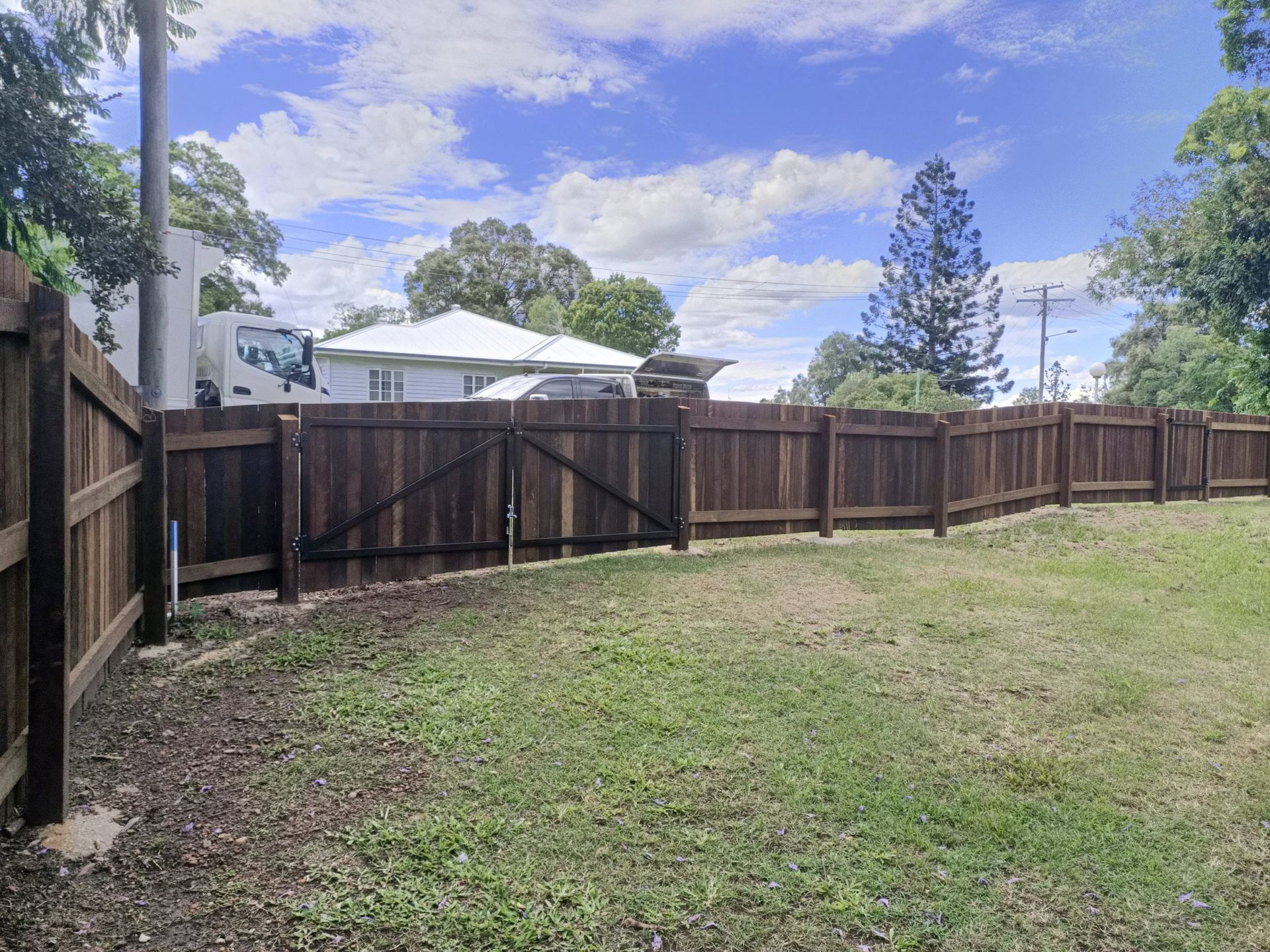 Brown Wooden Fence Encloses a Grassy Backyard — Quality Fences 4 U in Cooroy, QLD