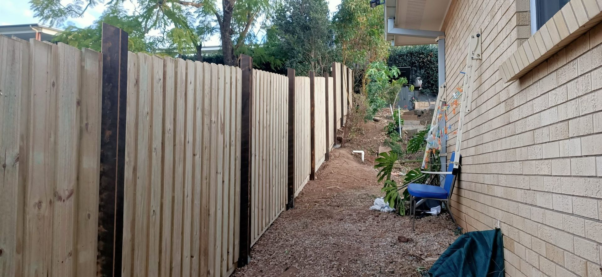 Wooden Fence Runs Along the Side of a Brick House — Quality Fences 4 U in Gympie, QLD