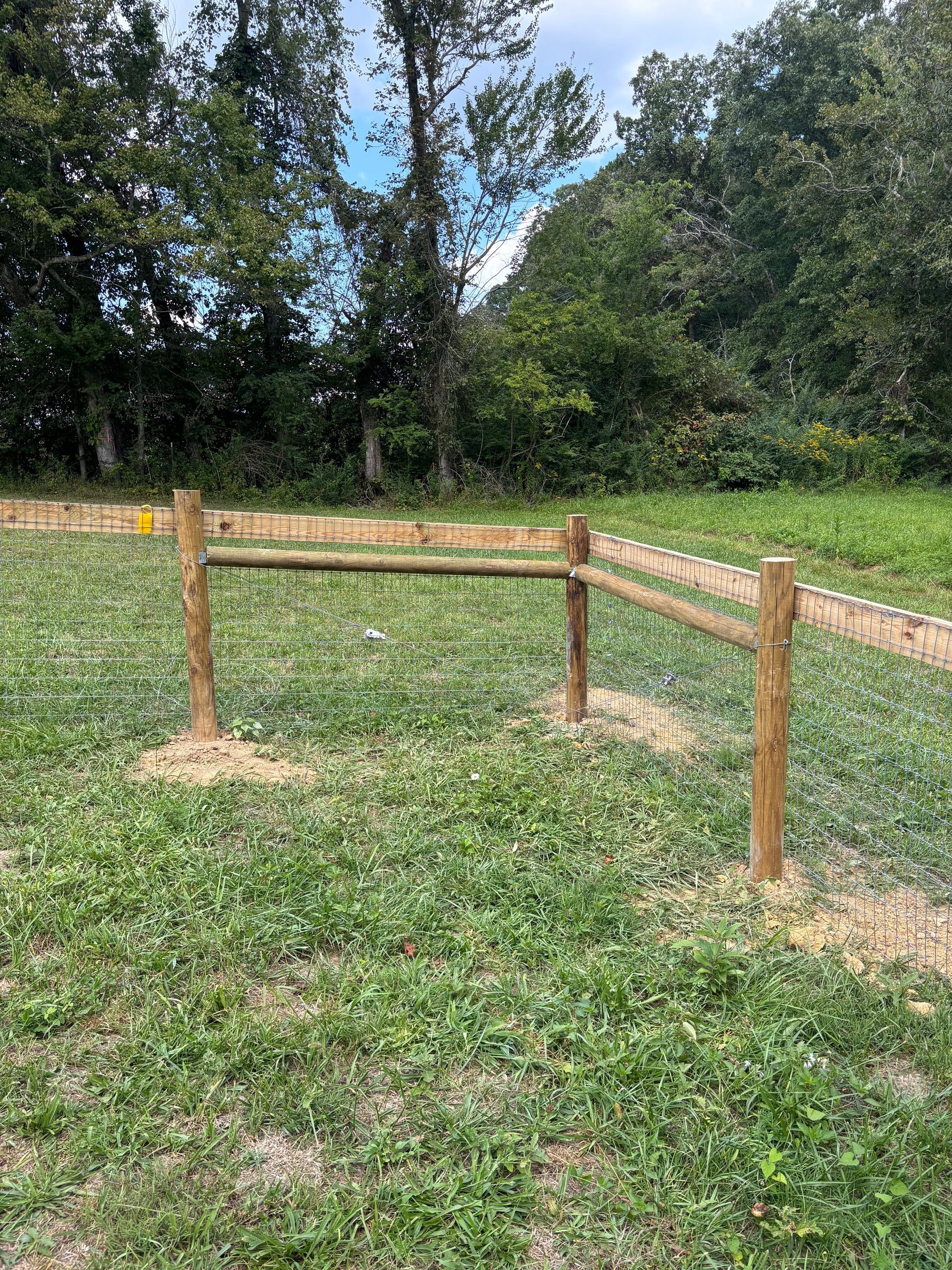 A wooden fence is sitting in the middle of a grassy field.
