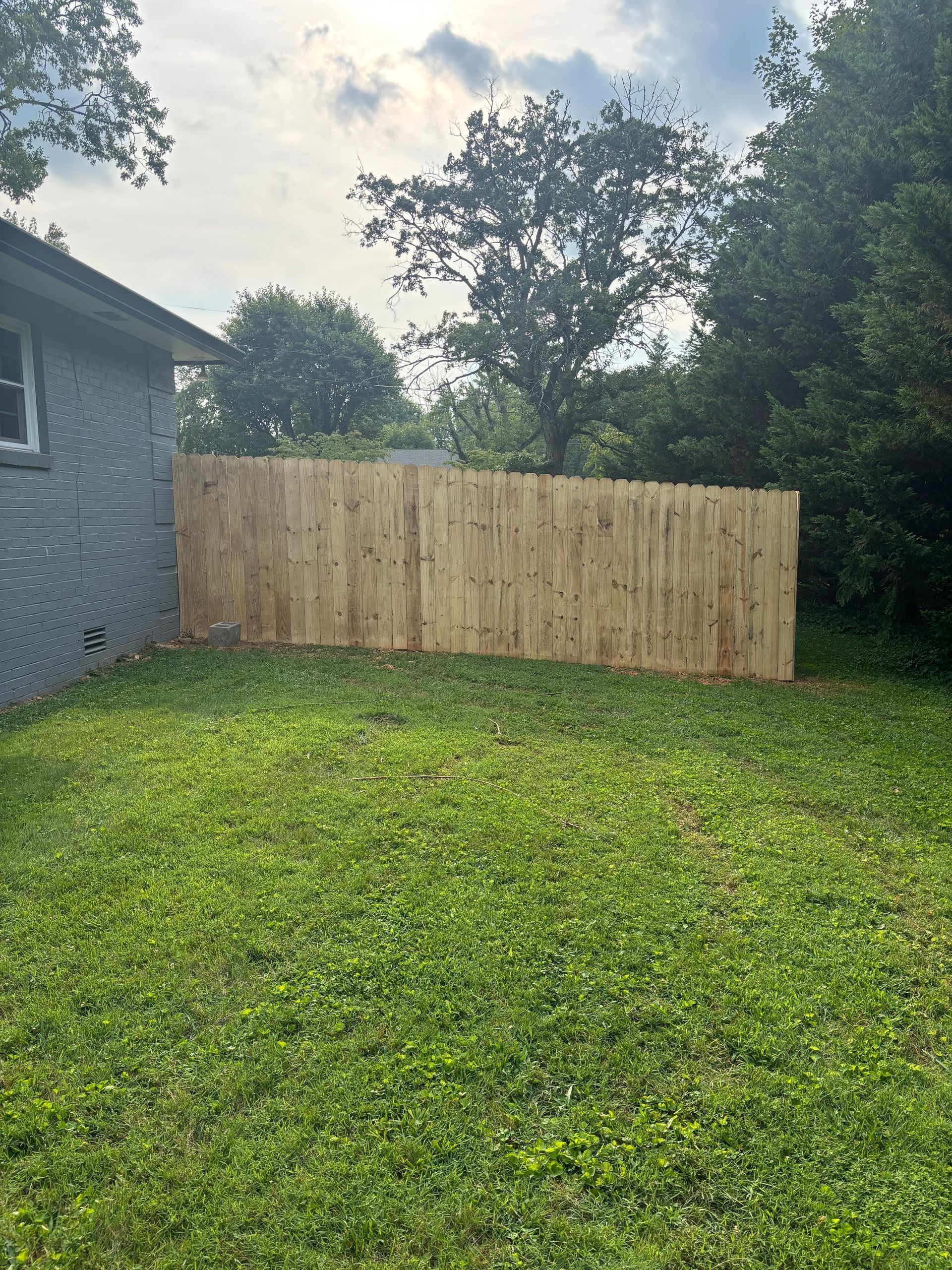 A wooden fence is in the backyard of a house.