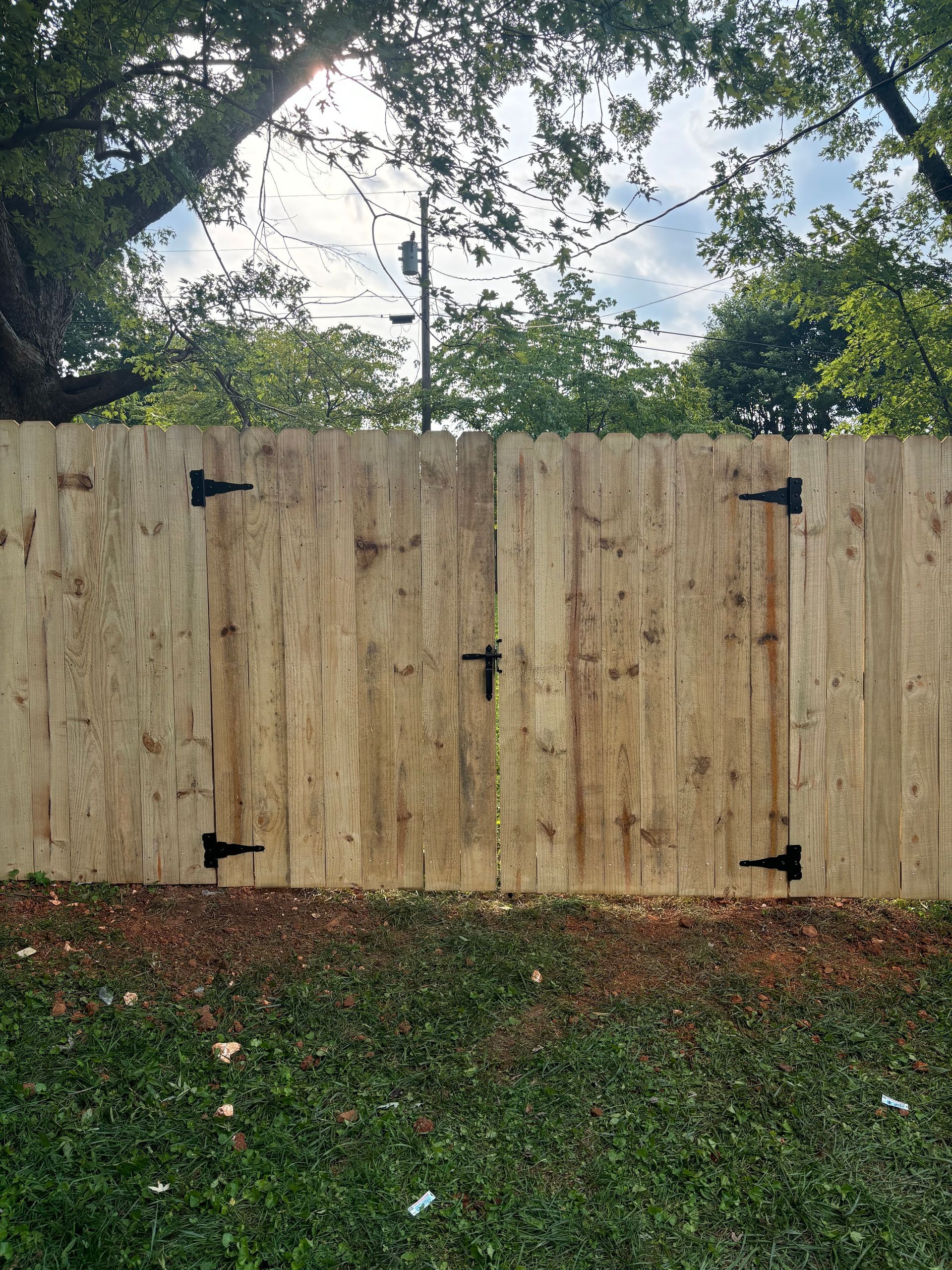 A wooden fence with a gate is sitting in the middle of a lush green field.