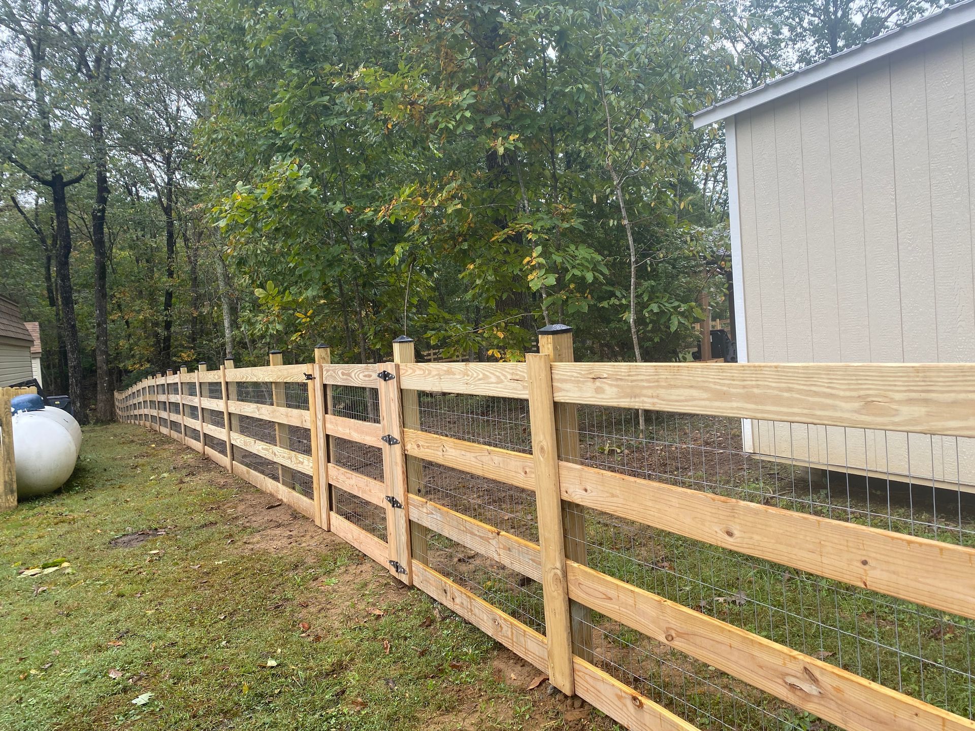 A wooden fence is sitting in the grass in front of a house.