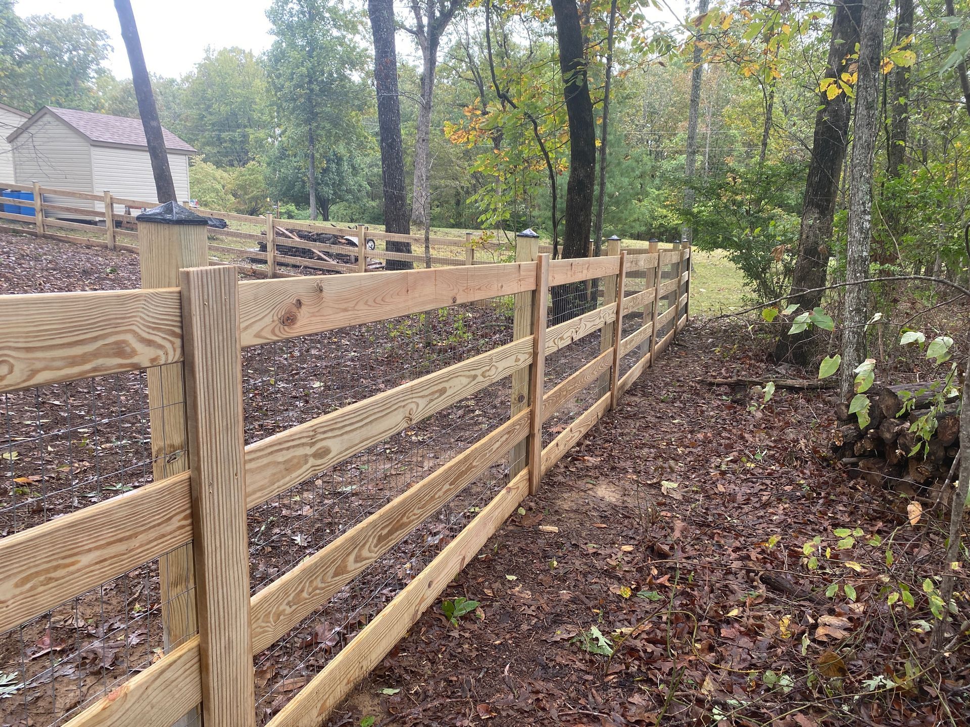 A wooden fence is surrounded by trees in the woods.