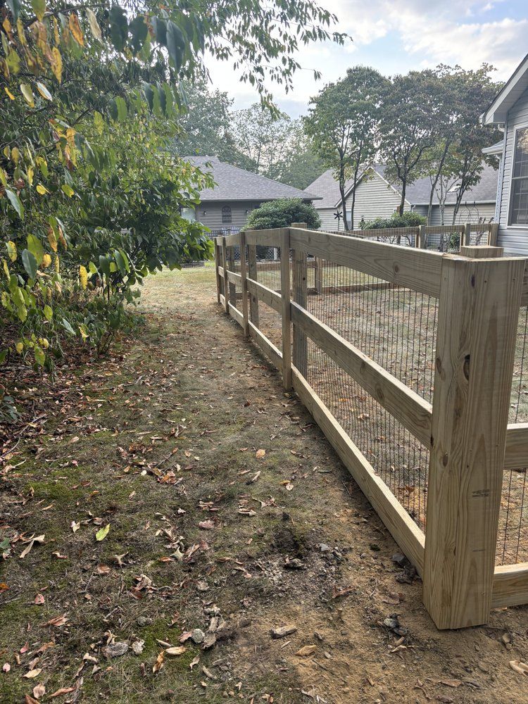 A wooden fence surrounds a dirt path in a backyard.