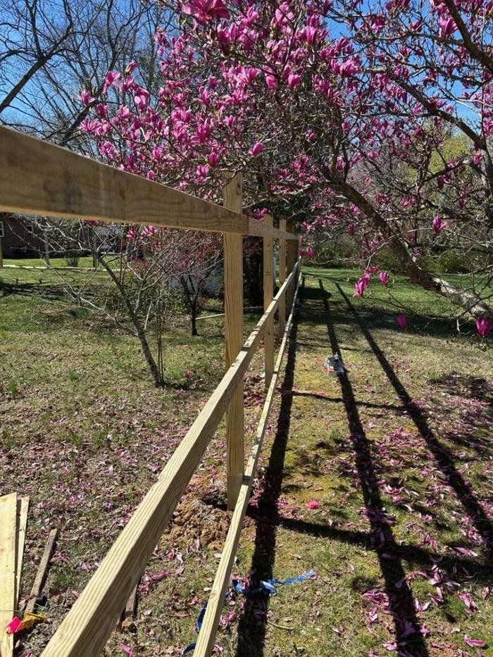 A wooden fence is surrounded by pink flowers in a field.