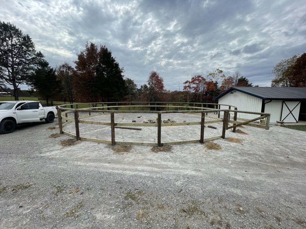 A white truck is parked in a gravel lot next to a wooden fence.