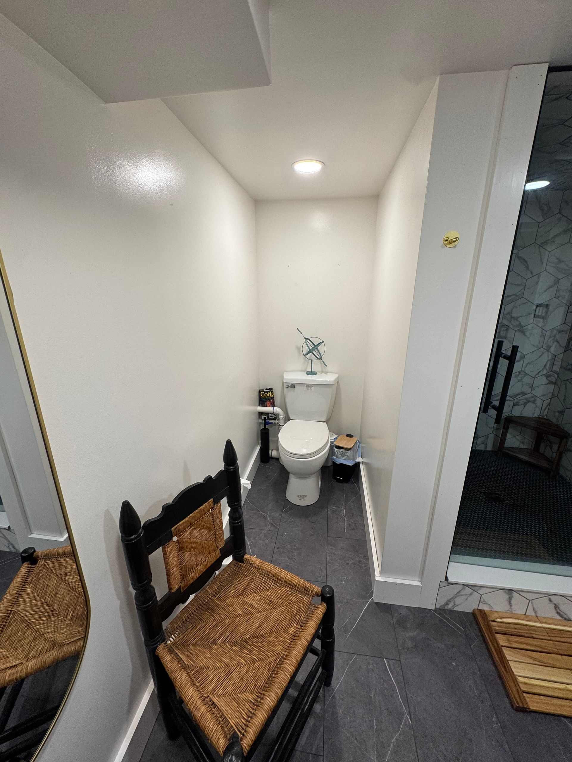 Man installing hardwood flooring, using a nail gun. Interior shot with living room in background.