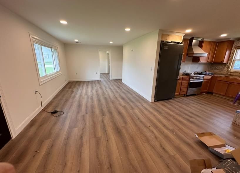 A man is hammering a piece of hardwood flooring.