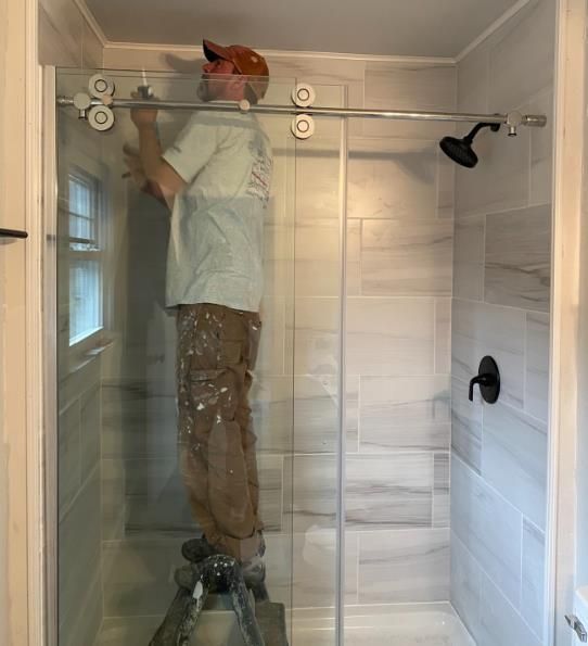 A man is hammering a piece of hardwood flooring.