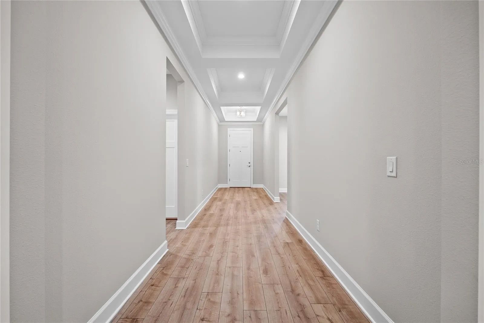 A long hallway with wooden floors and white walls in a house.