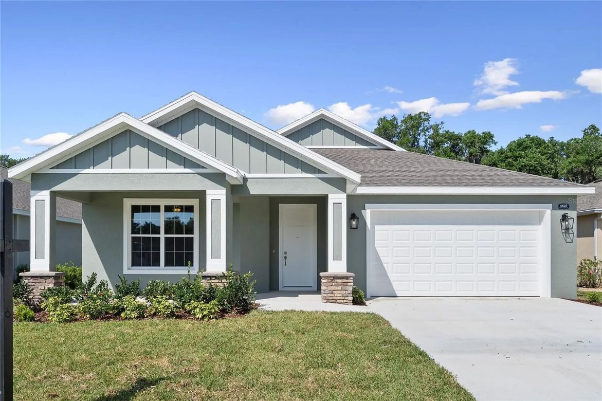 The front of a house with a white garage door and a blue sky in the background.