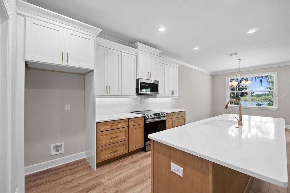 A kitchen with white cabinets , stainless steel appliances , and a large island.