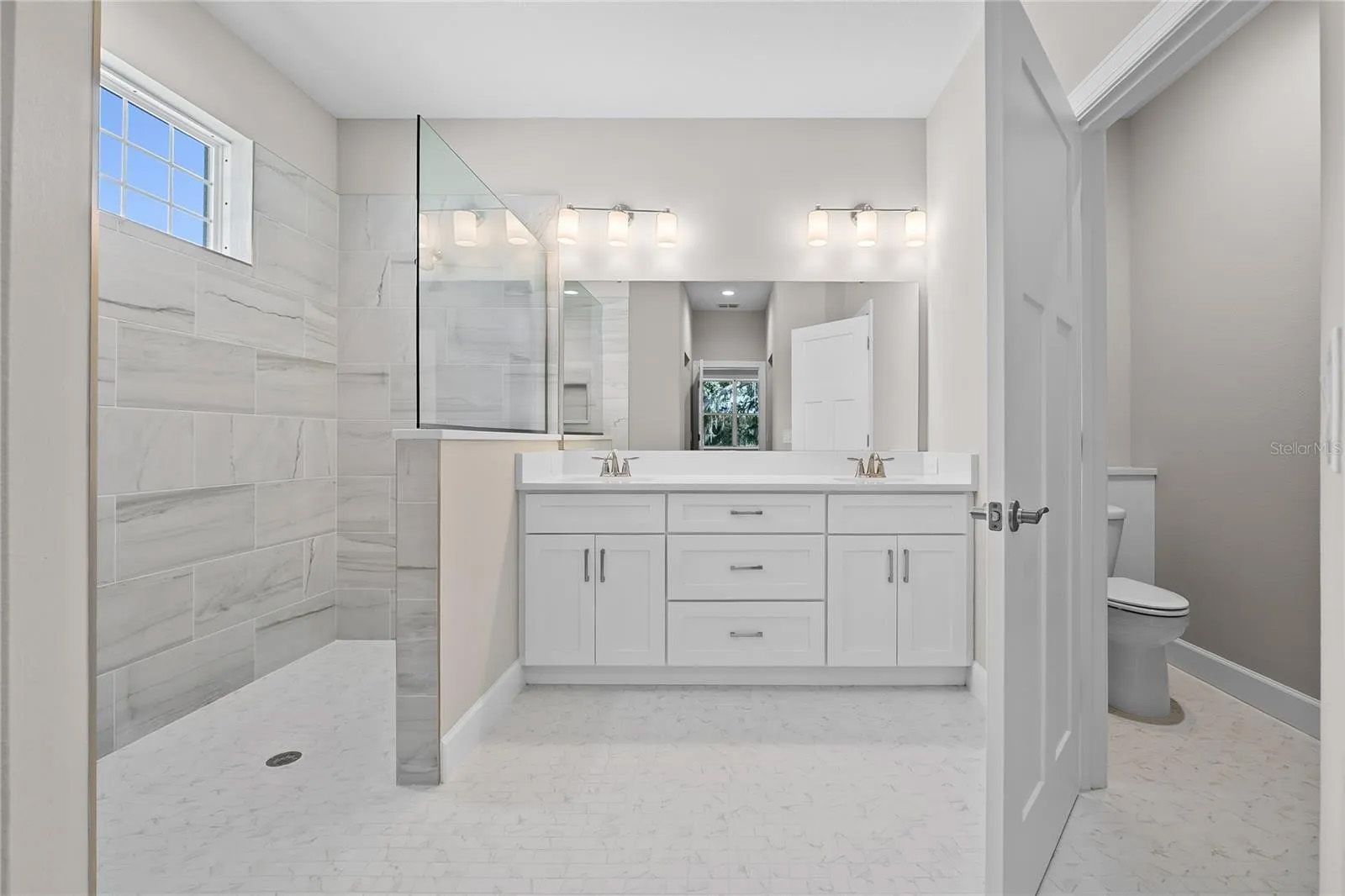 A bathroom with two sinks , a toilet , and a walk in shower.