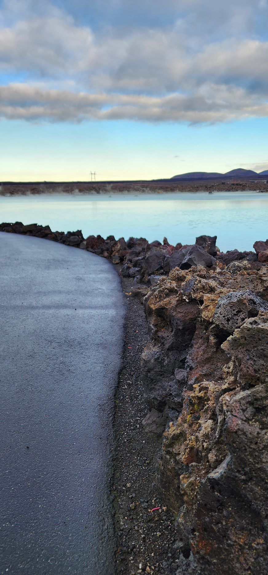 A road going through a rocky area next to a body of water.