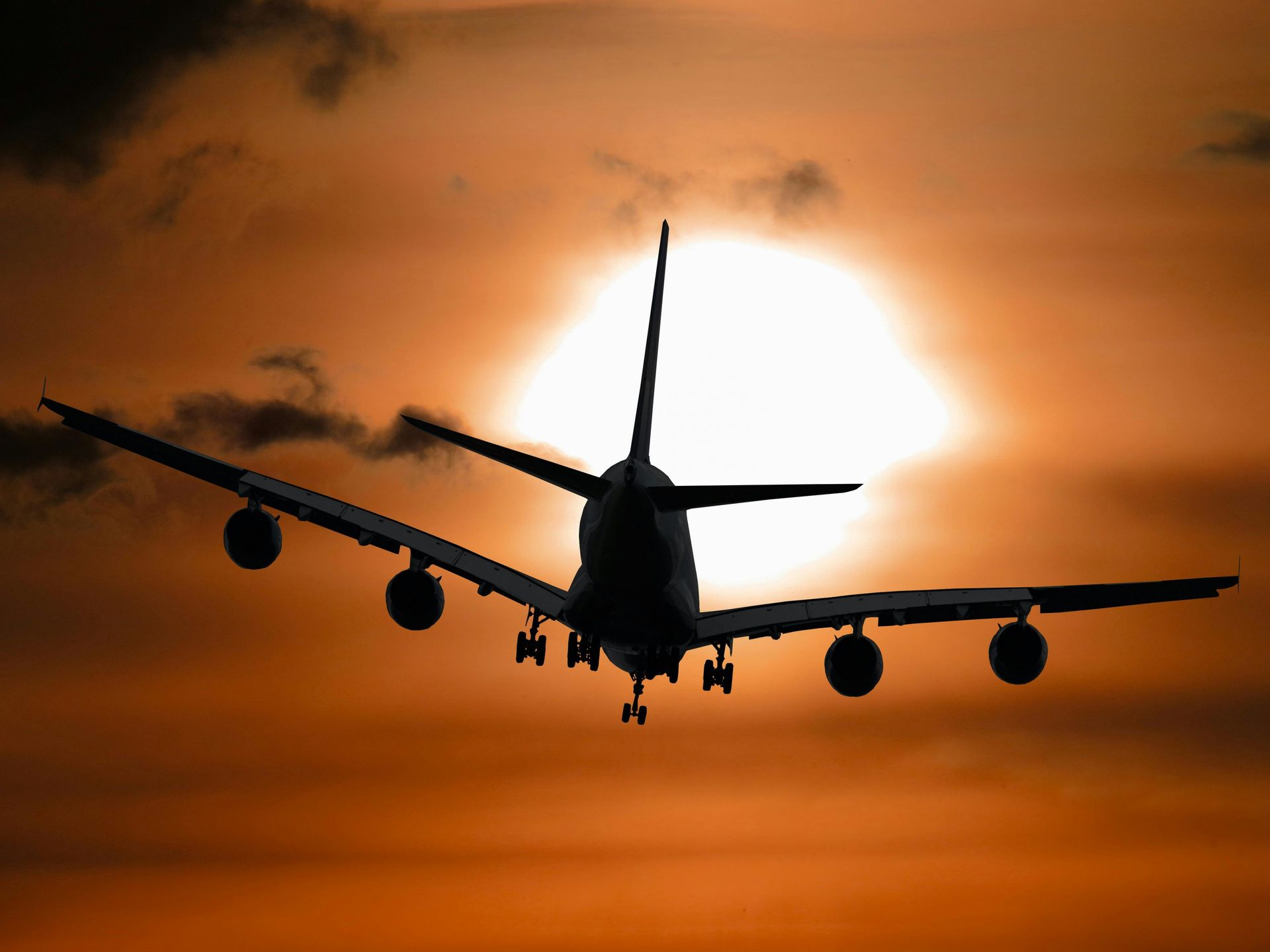 An airplane is flying in the sky at sunset.