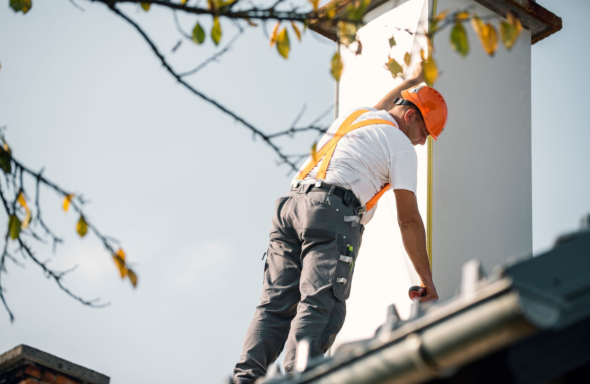 Roofer measuring chimney on roof top – Macungie, PA - Anytime Todd's Chimney Sweeping