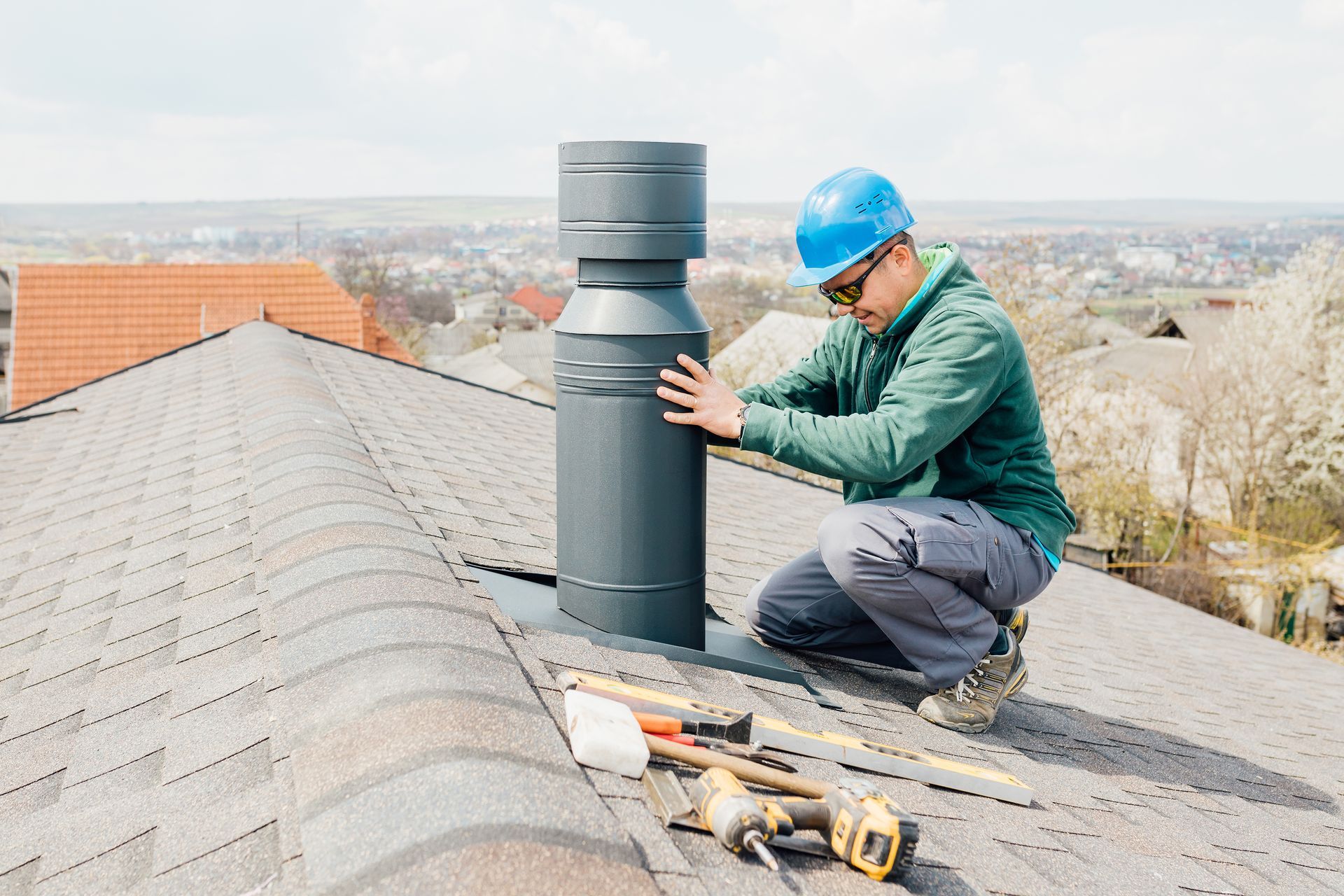 A man is installing a chimney on the roof of a house.