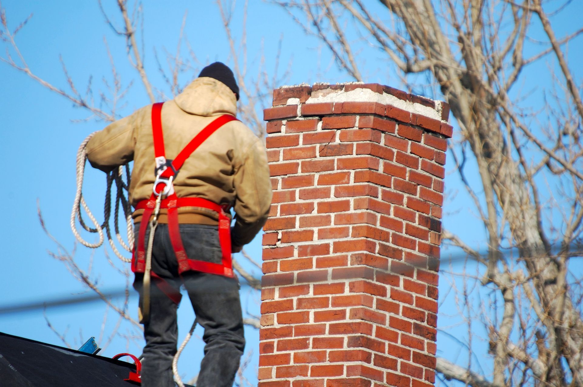 A man is standing on top of a brick chimney.