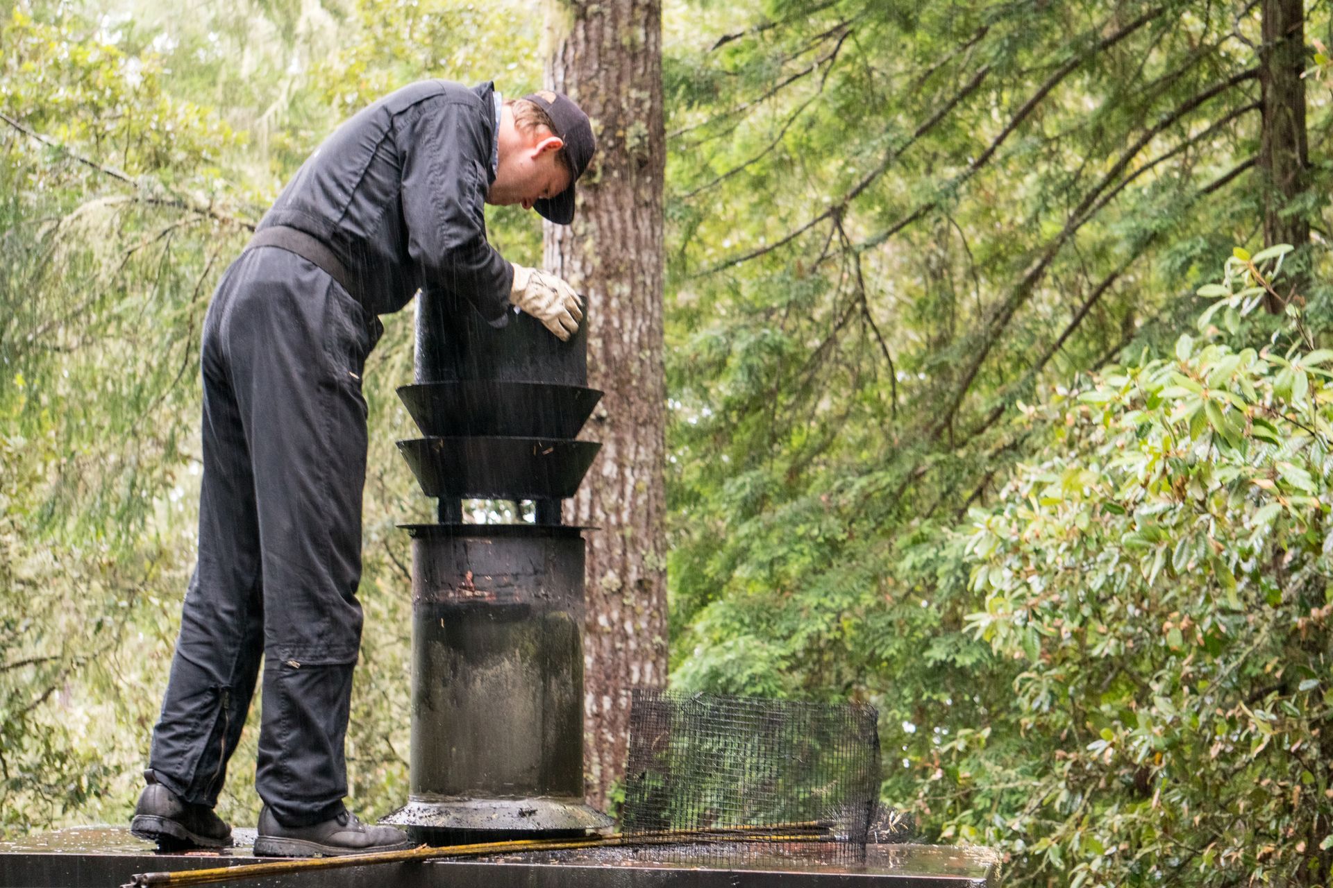 A man is cleaning a chimney in the woods.