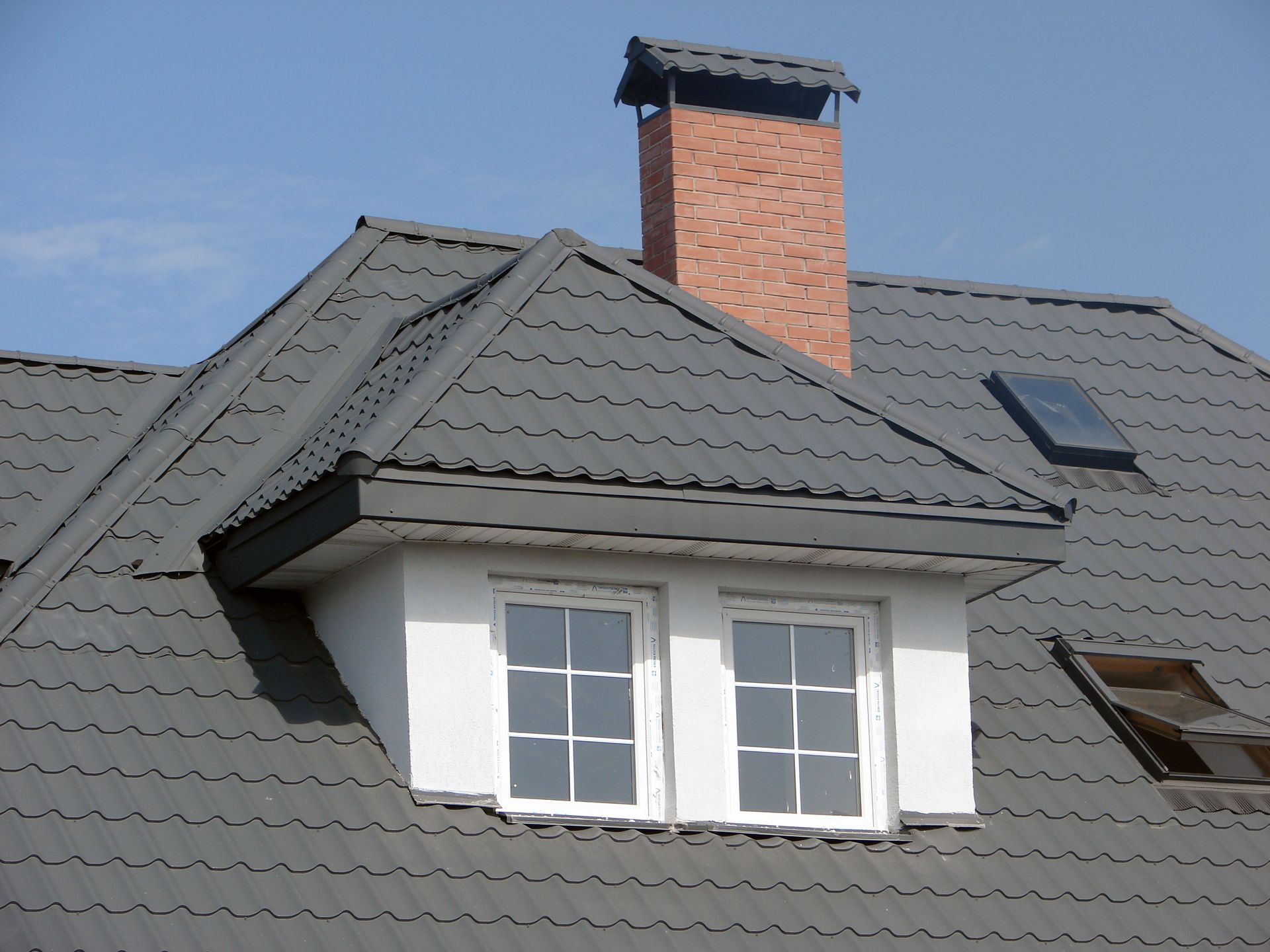 A roof with a chimney and two windows on it