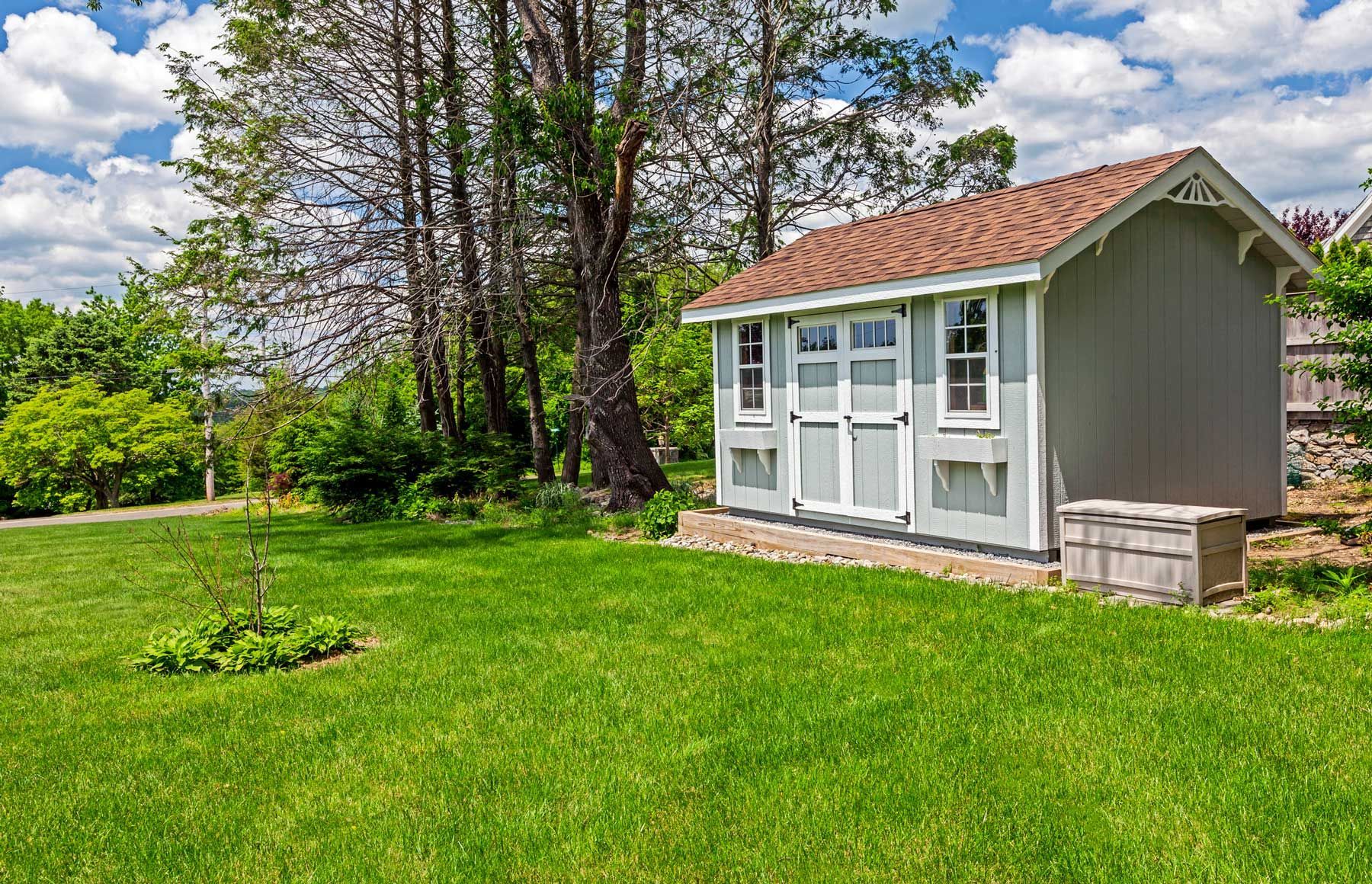 Gray shed with white trim, brown roof, and small windows.