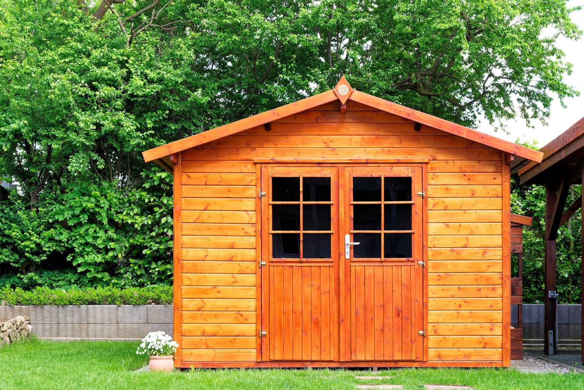 Wooden shed with double doors, set in a green yard.