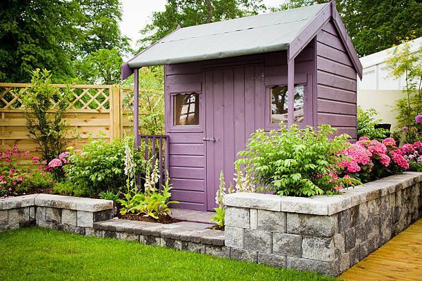 Purple garden shed with stone retaining wall.
