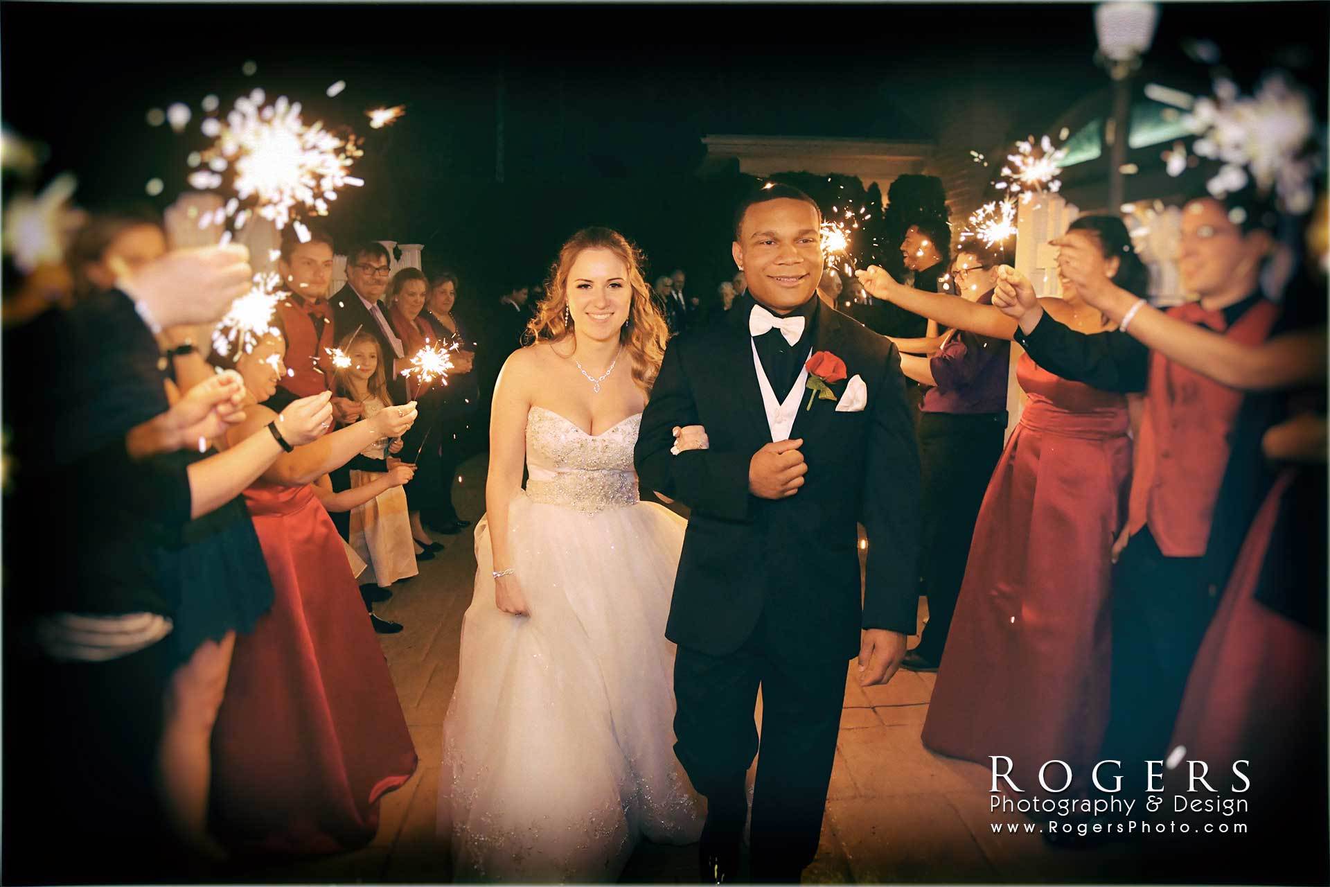 a bride and groom are walking through a tunnel of sparklers photographed by rogers photography & design