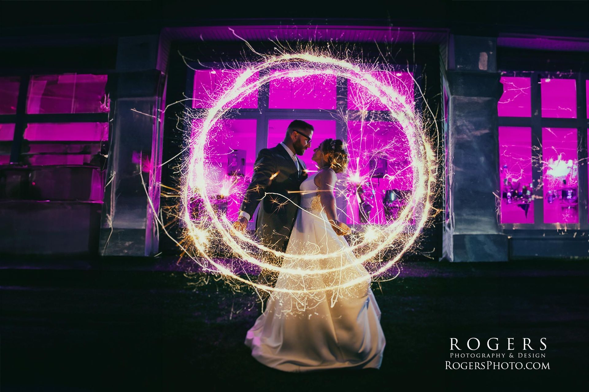 A bride and groom are surrounded by sparklers at their wedding at the Lake House wedding photographed by Rogers Photography in Connecticut.