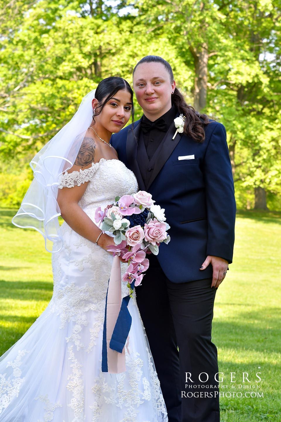 A same sex couple bride and bride pose for a picture in a field wedding photographed by Rogers Photography in Connecticut.