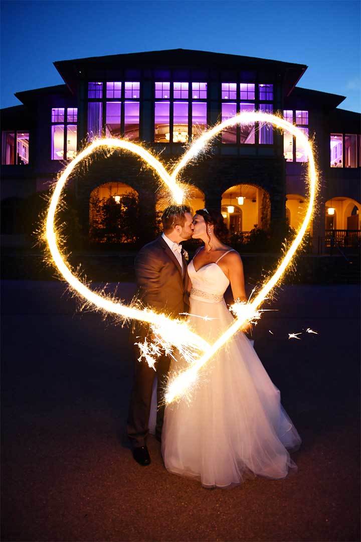 a bride and groom kiss while holding sparklers at lake of isles in Connecticut after photo retouching