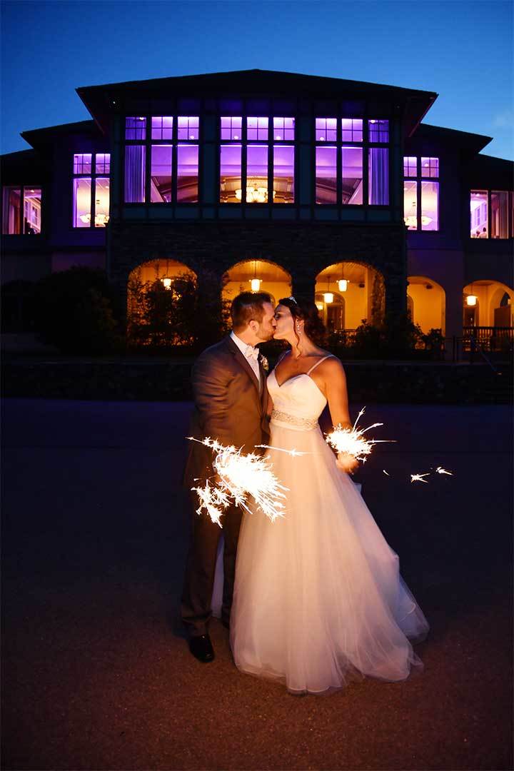 a bride and groom kiss while holding sparklers at lake of isles in Connecticut before photo retouching