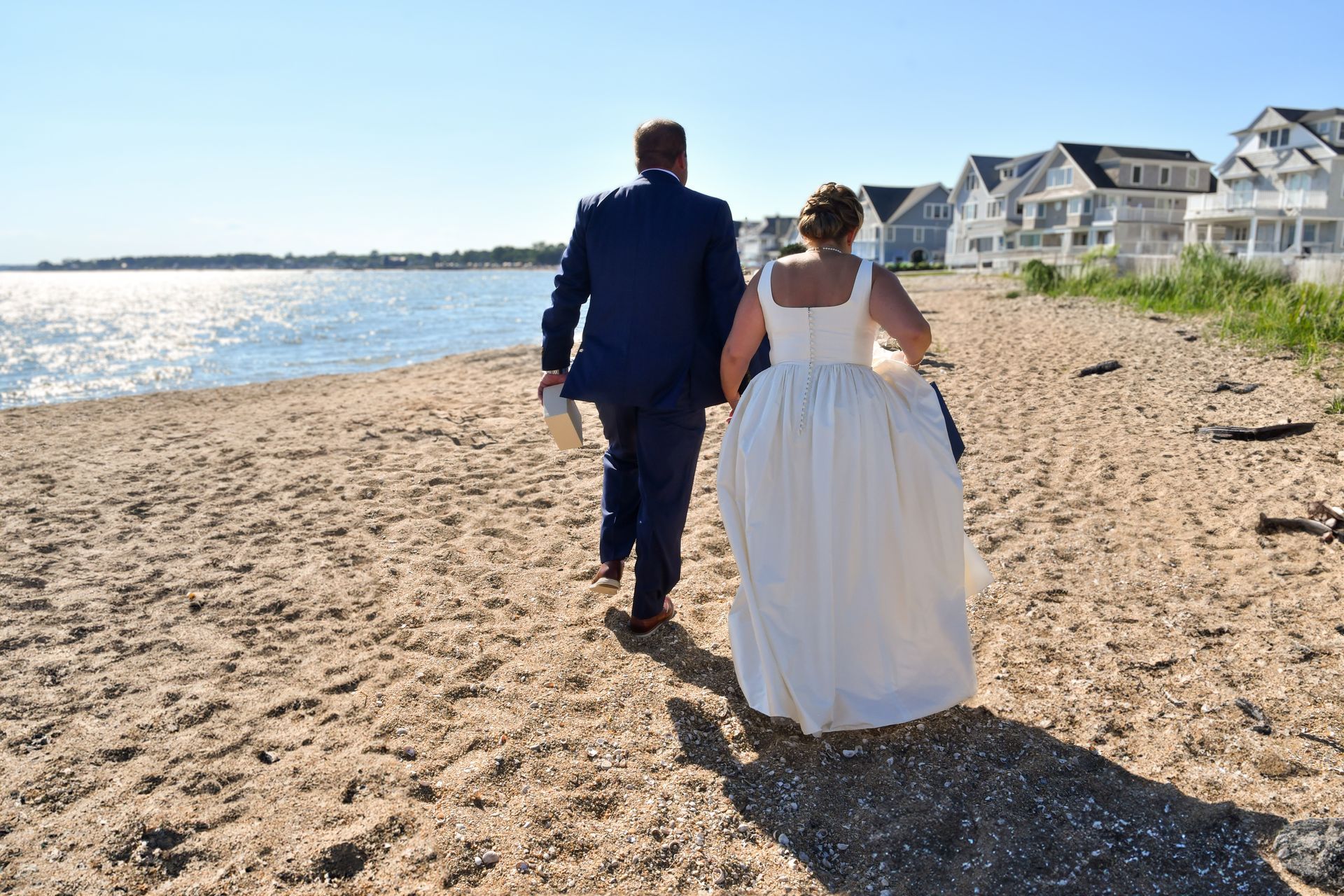 a bride and groom are walking on a beach full of people after major photo retouching