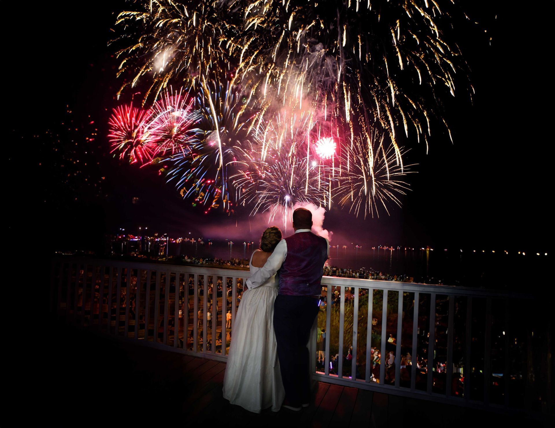 a bride and groom watch fireworks on a balcony after major photo retouching