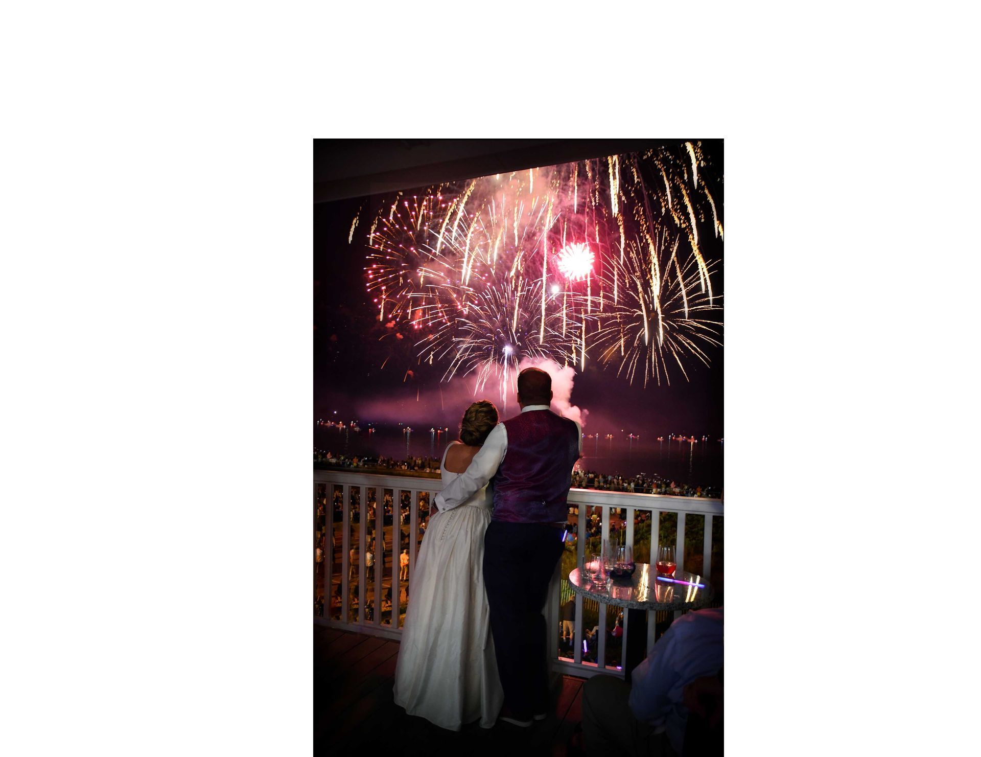 a bride and groom watch fireworks on a balcony before major photo retouching