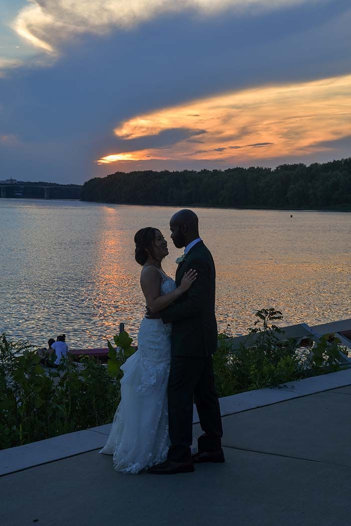 a bride and groom are dancing in front of a lake at sunset before major photo retouching