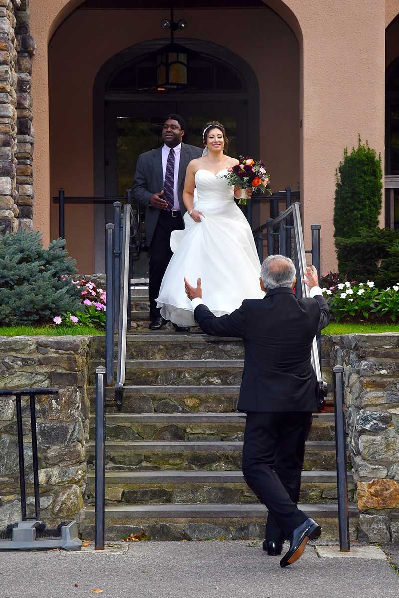 a bride is walking down a set of stairs to meet her father before major photo retouching