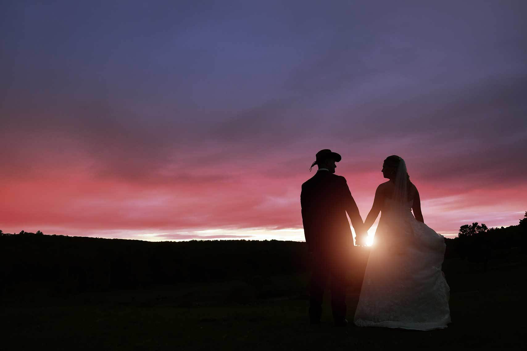 a bride and groom standing in a field holding hands at sunset after photo retouching