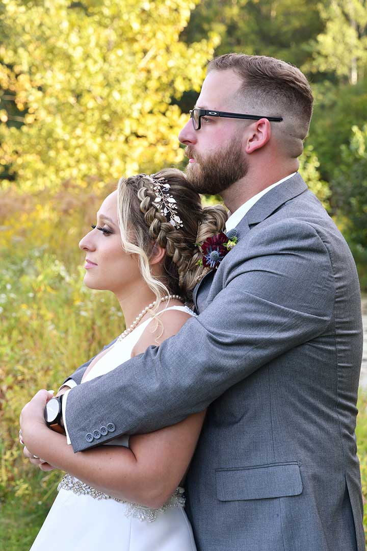A bride and groom are posing for a picture on their wedding day in a field of flowers at The LakeHouse wedding photographed by Rogers Photography in Connecticut.