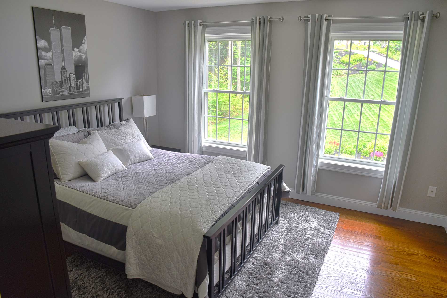A bedroom with a large bed and two windows for Real Estate photography by Rogers Photography.
