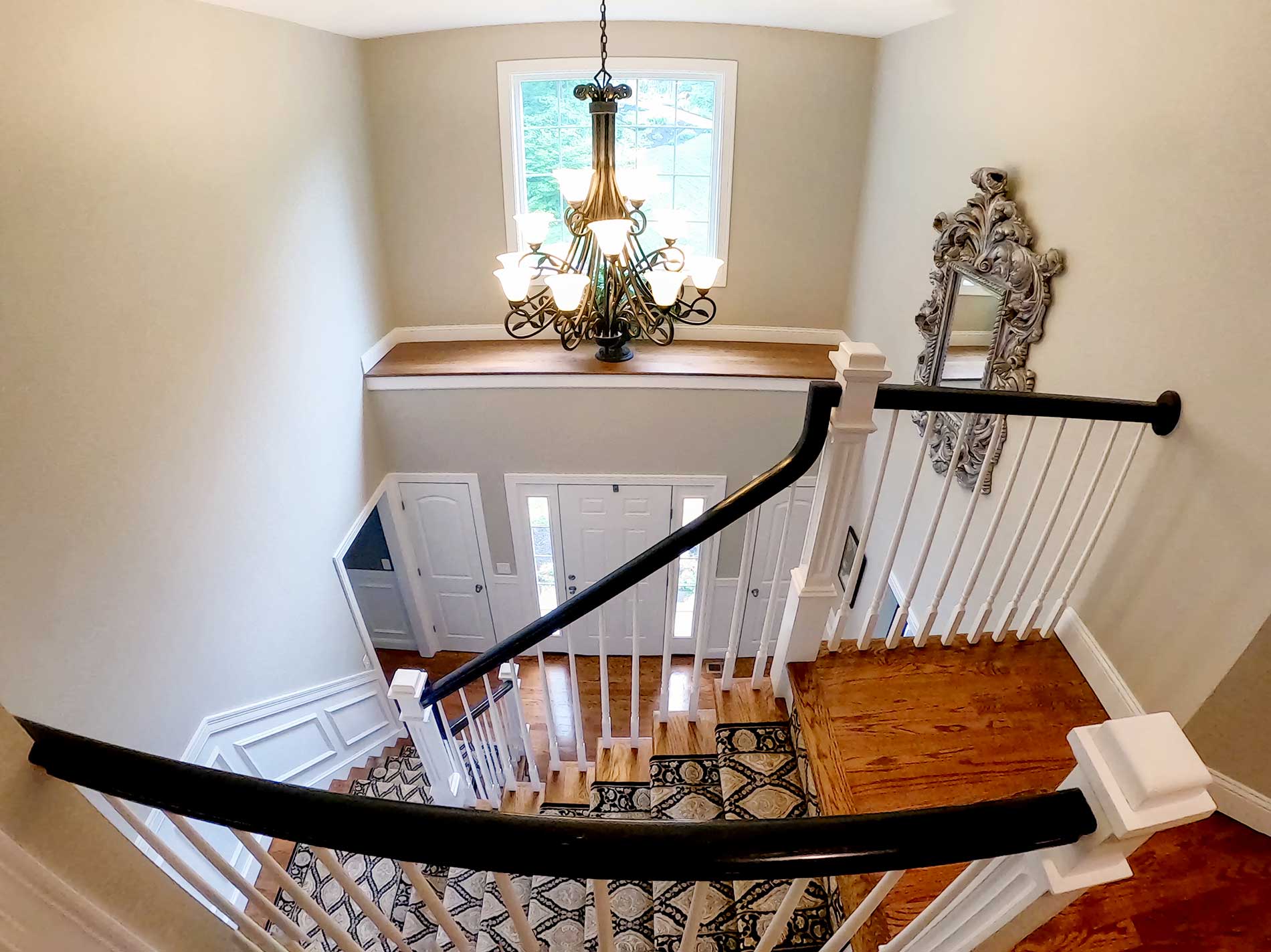 An aerial view of a staircase with a chandelier hanging from the ceiling for Real Estate photography by Rogers Photography.