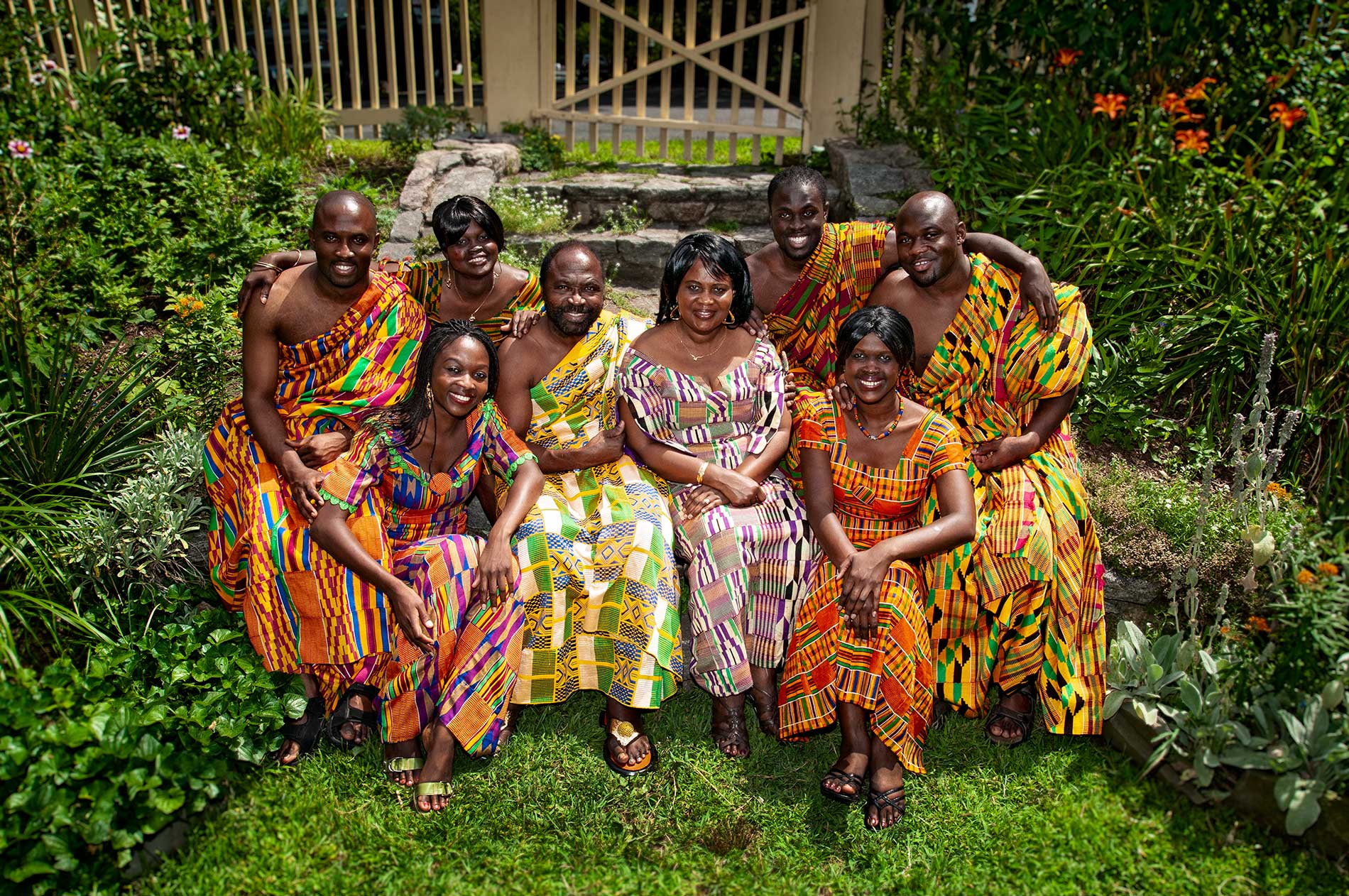 A group portrait people posing for a picture in a garden wearing traditional African clothing by Rogers Photography.