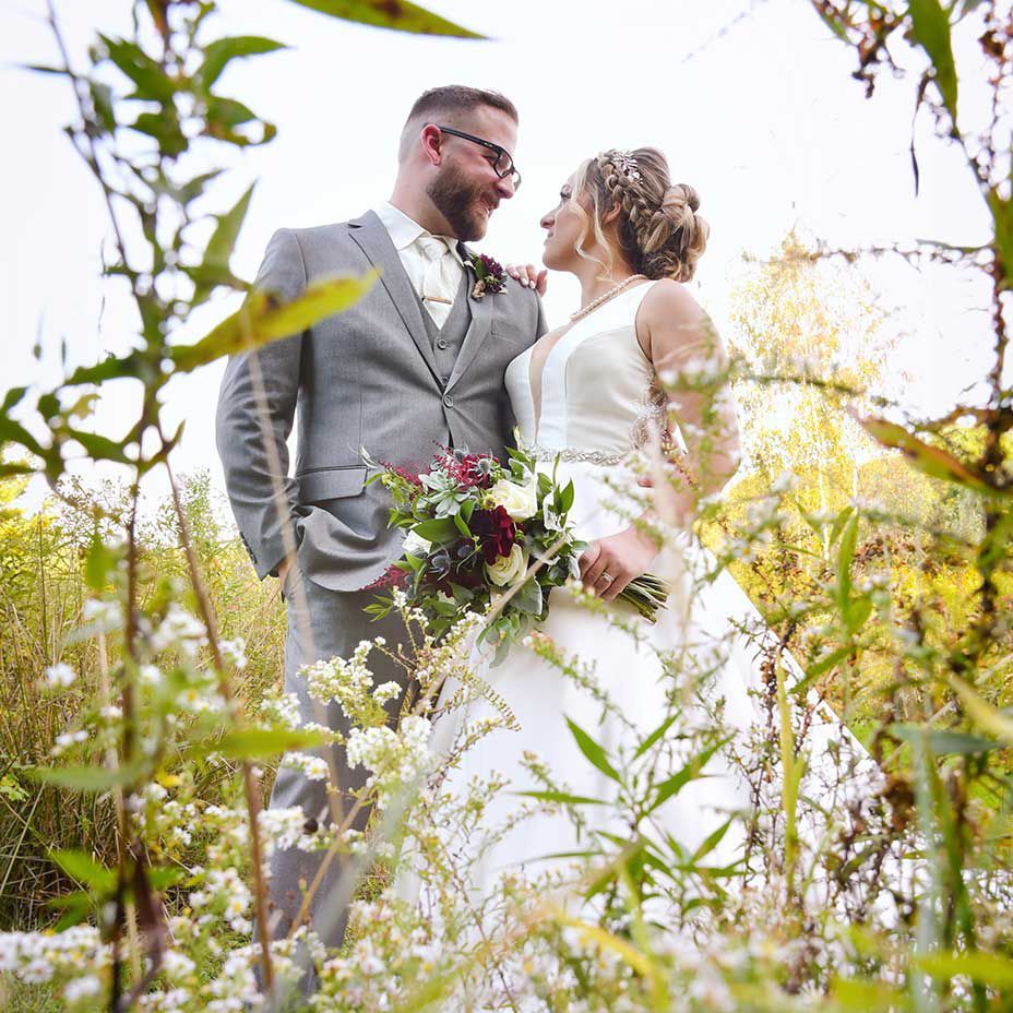 A bride and groom are posing for a picture in a field of flowers at The Lake House wedding photography by Connecticut Wedding Photographers Rogers Photography.