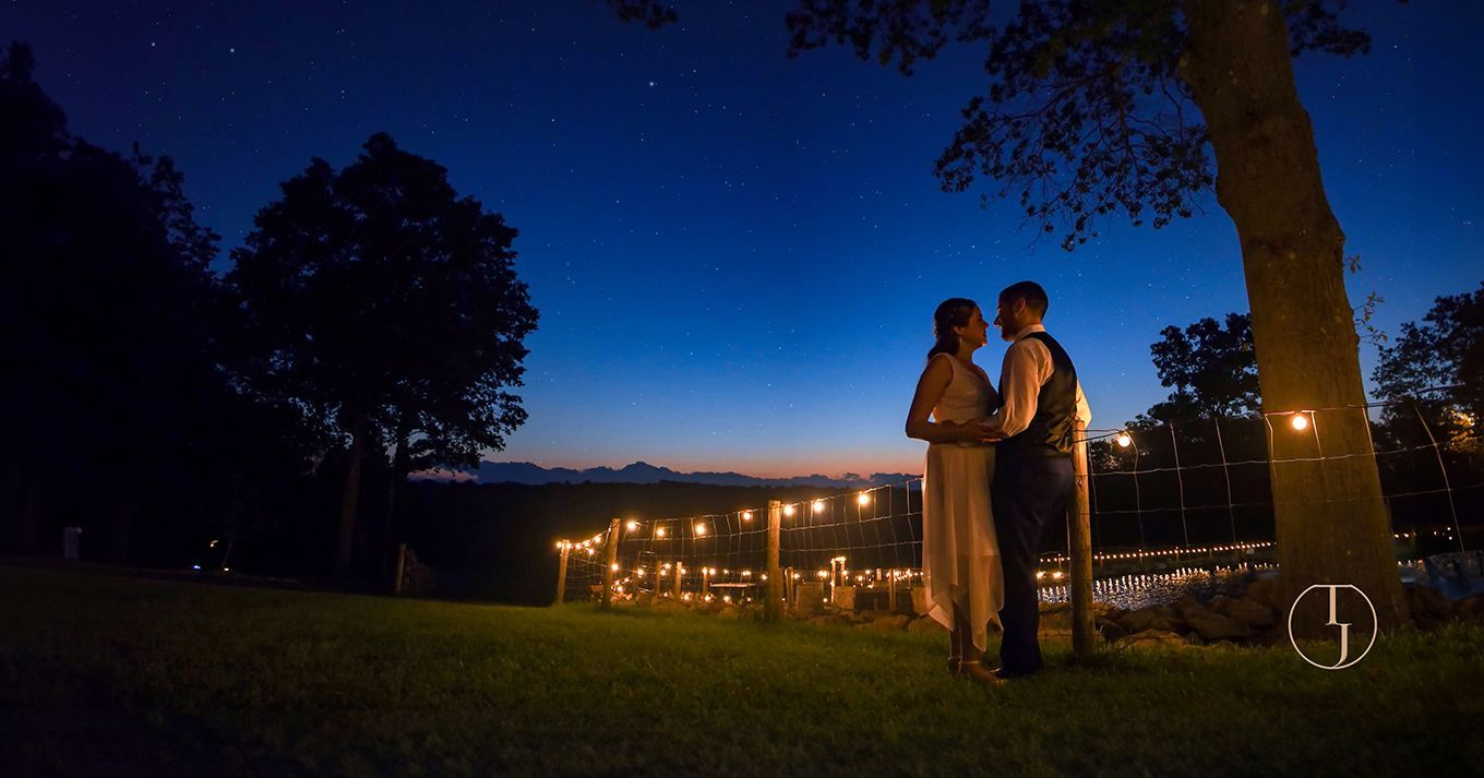 A bride and groom are standing under a tree at with stars in the sky at sunset at Nuzzo's Farm wedding photography by Connecticut Wedding Photographers Rogers Photography.