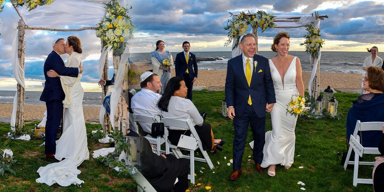 A bride and groom kiss during their wedding ceremony on the beach at Madison Beach Hotel wedding photography by Connecticut Photographers Rogers Photography