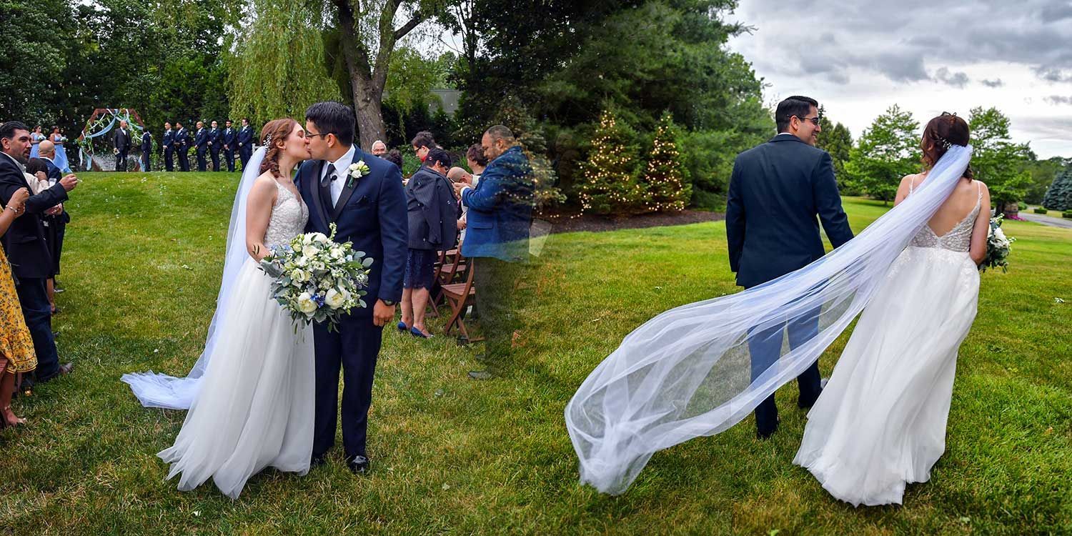 A bride and groom walking the grass with their veil blowing in the wind at Woodwinds wedding photography by Connecticut Wedding Photographers Rogers Photography.