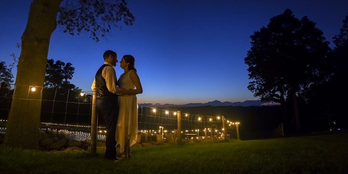 A bride and groom are standing under a tree at sunset with stars at Nuzzo's Farm wedding photography by Connecticut Wedding Photographers Rogers Photography.